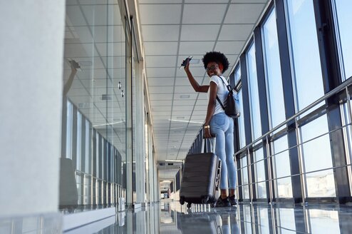 A woman stands in an aiport and waves.